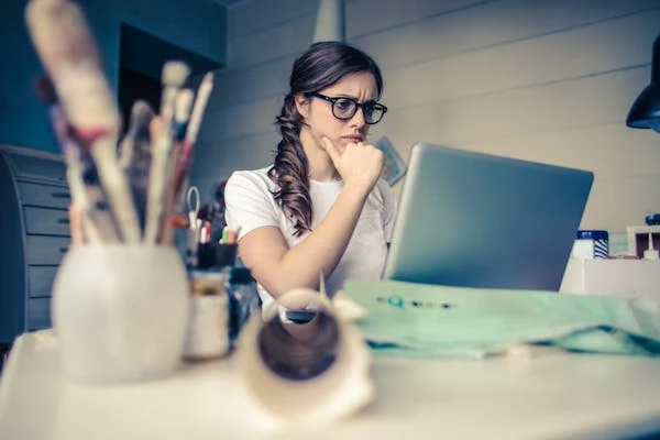Cognitive Behavioral Therapy: 7 Powerful Ways CBT Can Transform Your Mindset 2 Young woman reflecting while working on a laptop, illustrating the self-awareness and thought analysis promoted by Cognitive Behavioral Therapy